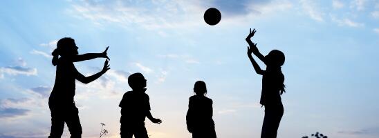 Silhouettes of children playing with ball